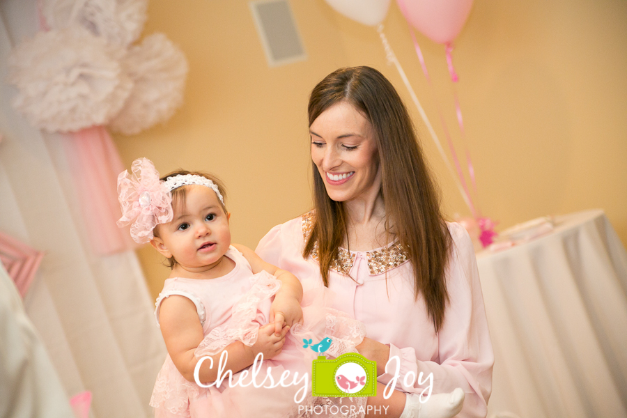 Baby J's mother holds her at the 1st birthday party.