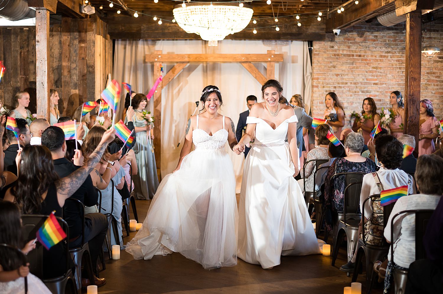 Rainbow flags waving as brides walk down wedding aisle at The Haight.