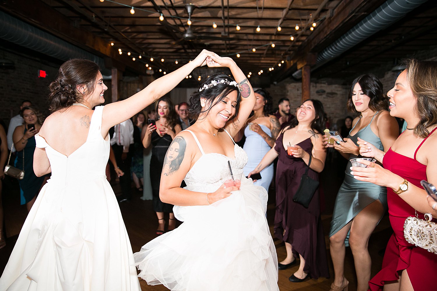 Brides dance together at wedding reception.