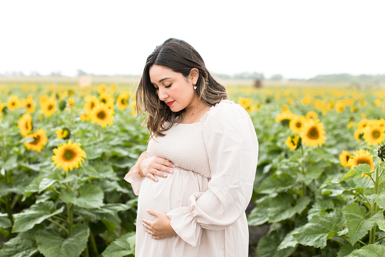 Mom stands in sunflower field for maternity photos