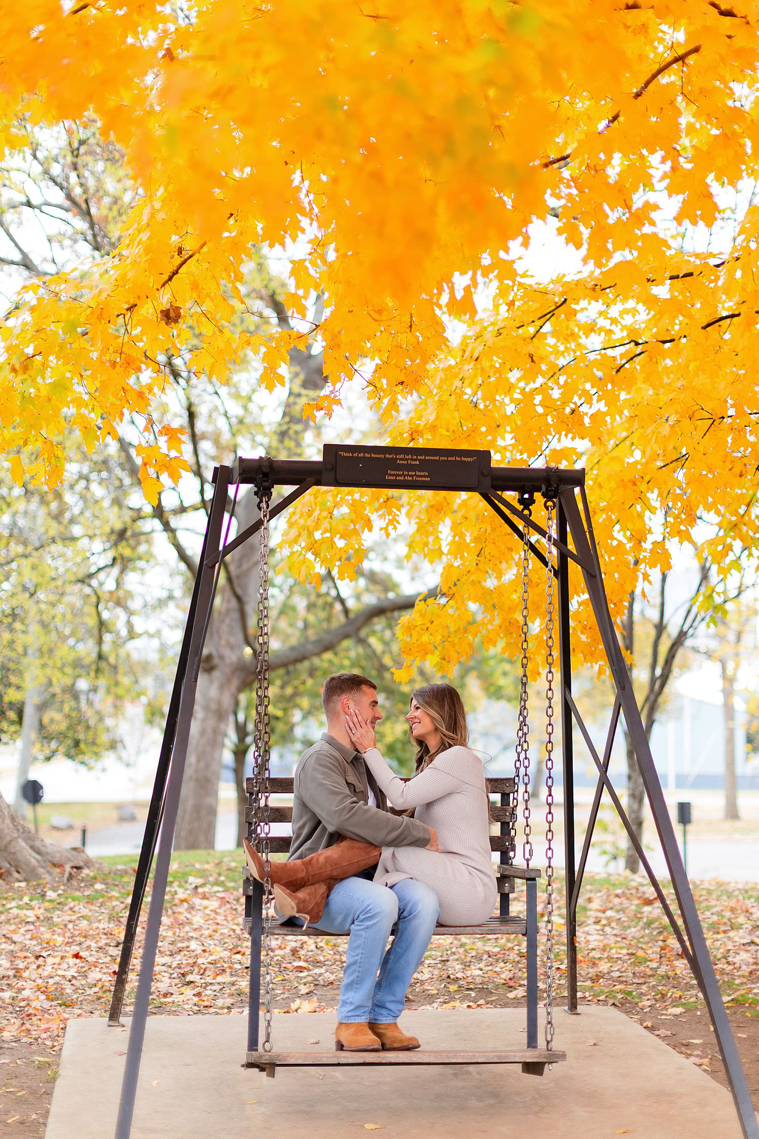 Engaged couple sits on bench at Centennial Park.