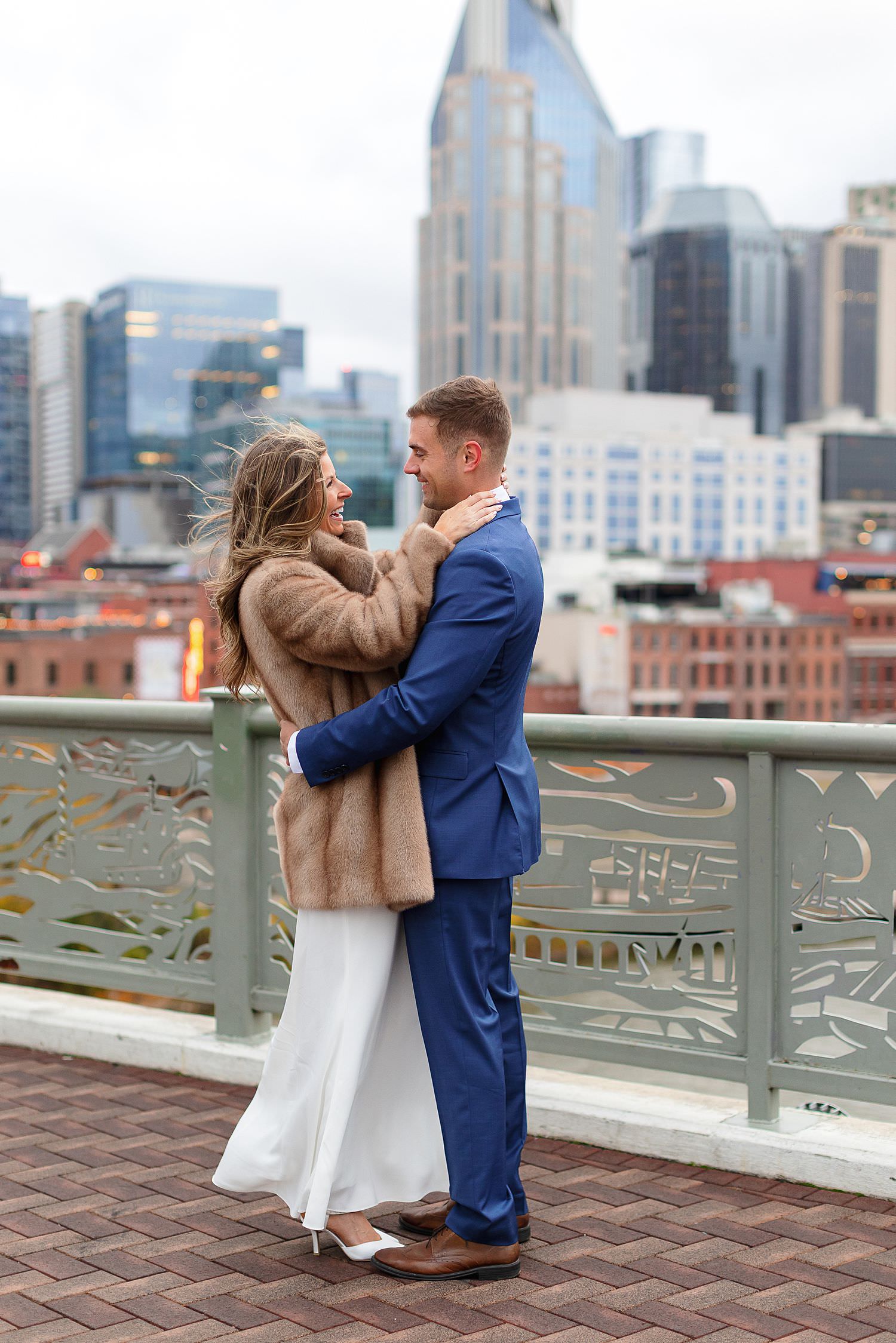 Nashville engagement photographer capturing couple on Pedestrian Bridge with city skyline.